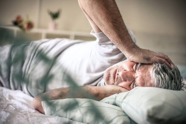 Senior man lying on bed and having headache. Space for copy.