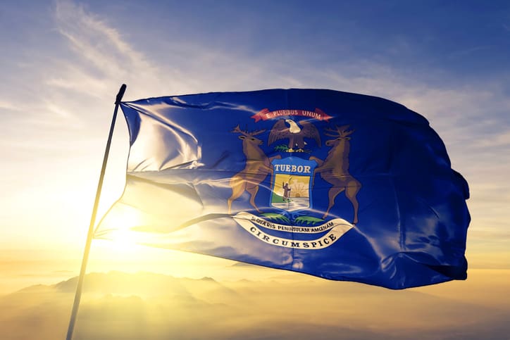 Michigan state of United States flag on flagpole textile cloth fabric waving on the top sunrise mist fog