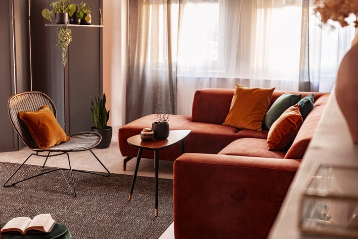Small coffee table in front of comfortable corner sofa in autumn colored living room interior