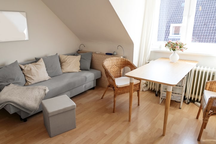Small attic apartment for a female student with desk, chairs and a sofa bed, housing and home office concept, copy space, selected focus